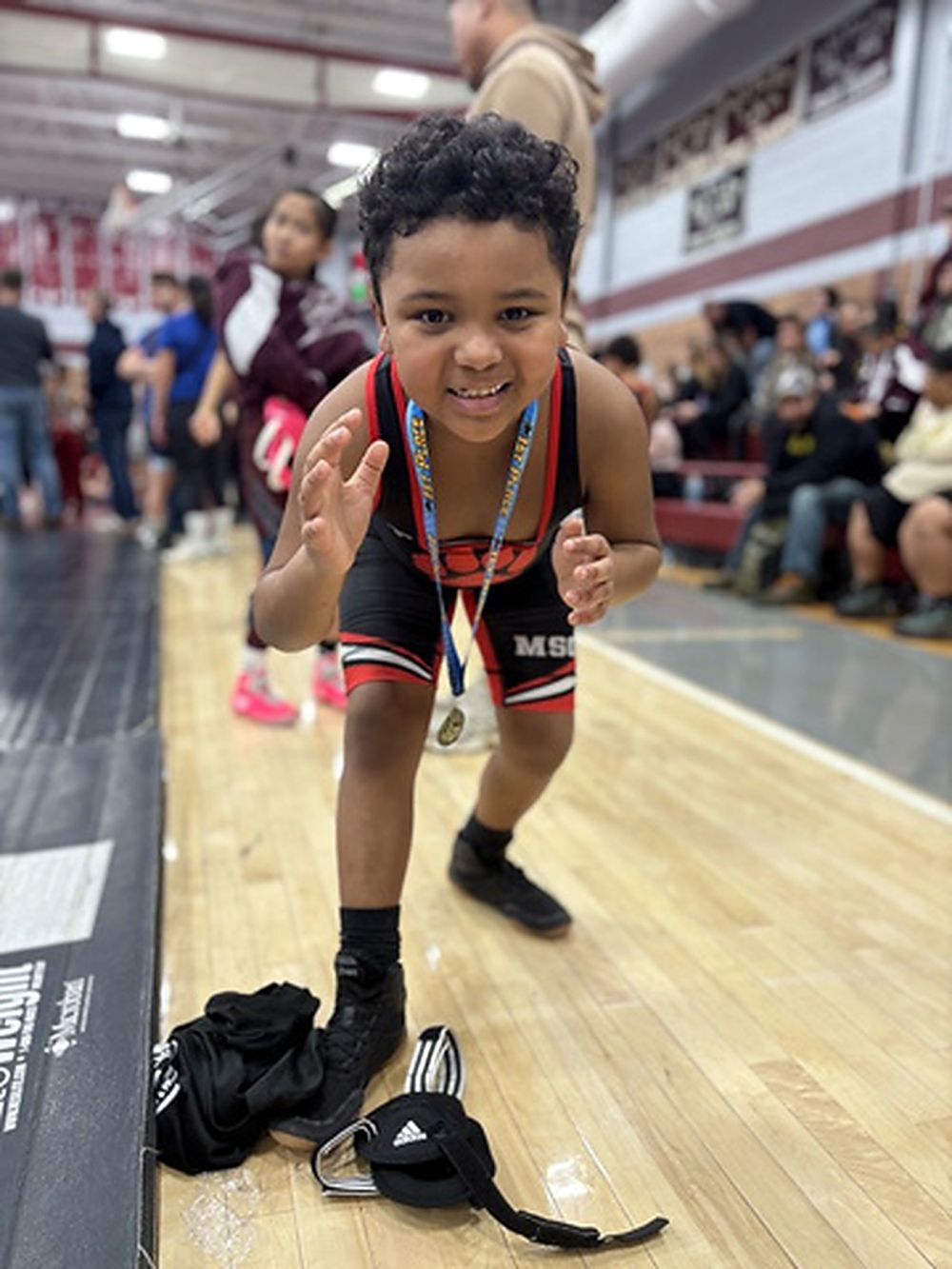 A young MSO wrestler in a singlet grinning with a medal around their neck.
